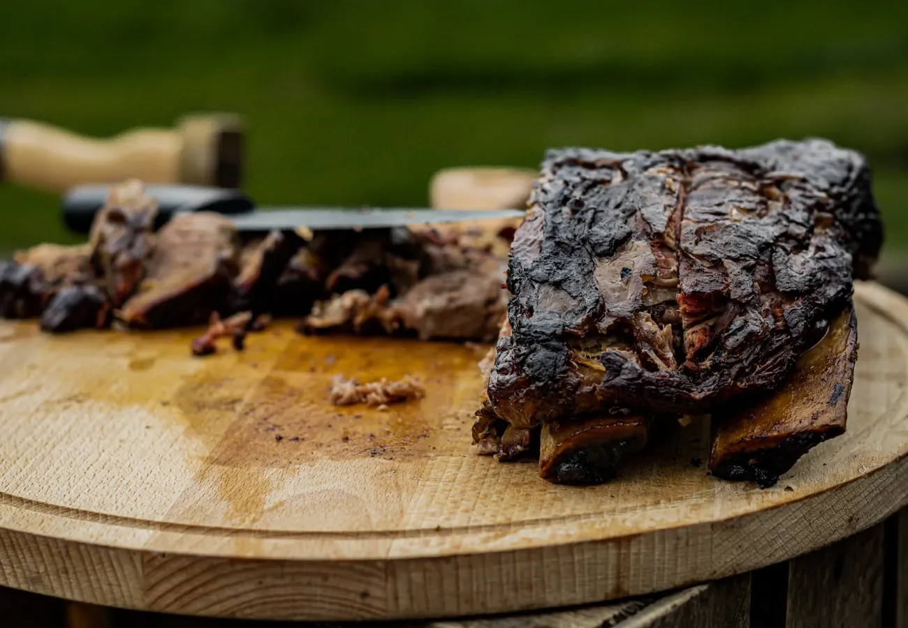 Gerookte beef short ribs op een houten snijplank, aangesneden voor BBQ catering op locatie van Smoke ‘N Roast